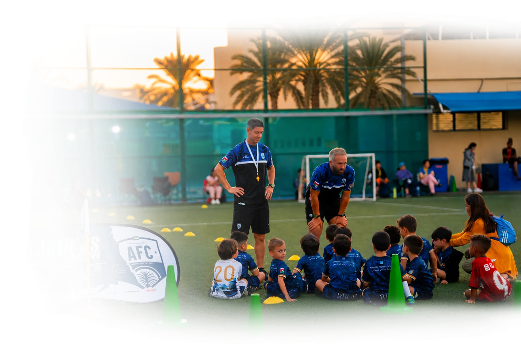 Two AFC coaches running a session with the youngest players sitting on the pitch